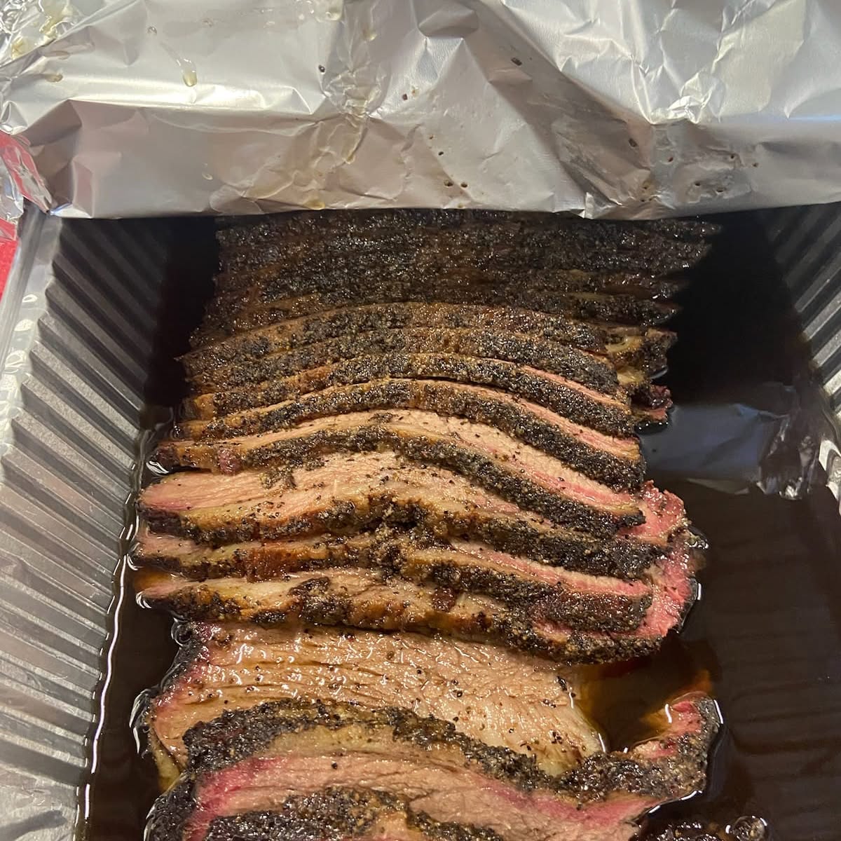 Sliced smoked brisket with a dark bark and smoke ring