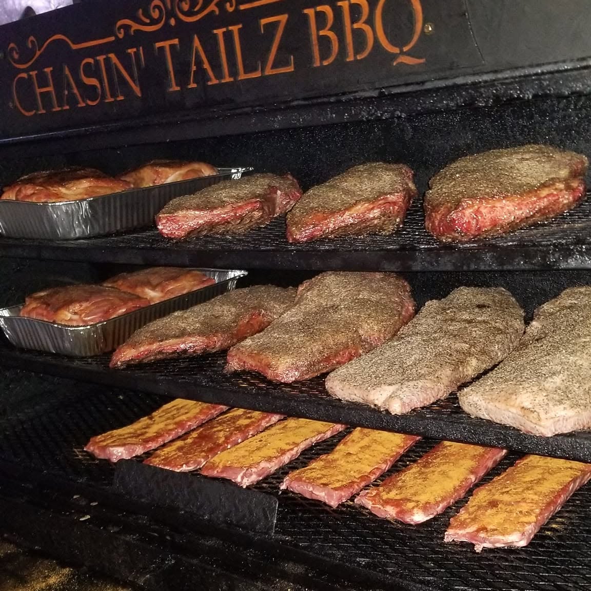 Smoker loaded with Chasin Tailz BBQ meats